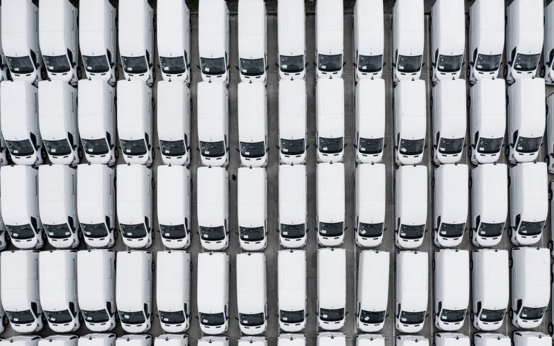 Aerial view of rows of new white vans parked together